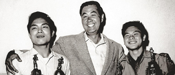 Paul Whang standing with two students holding trophies 